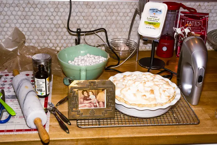 A kitchen scene featuring a merengue pie -- and a few of the ingredients needed to make it -- and framed photograph of a grandmother and her young grandson.